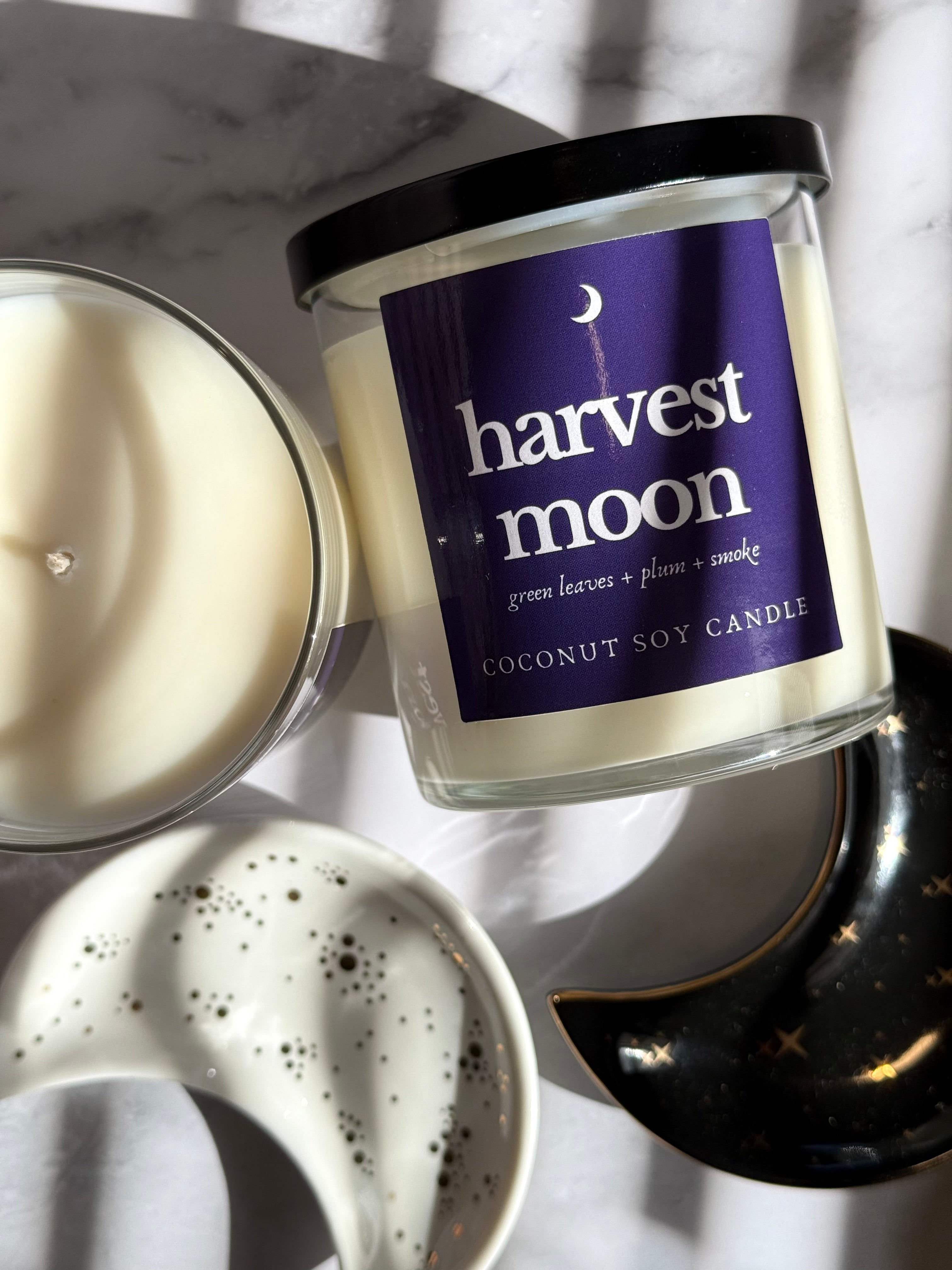 Coconut soy candle labeled 'harvest moon' on a marble surface with a blurred background